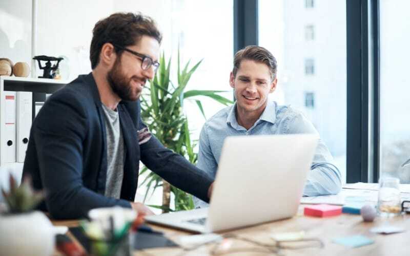 Two young casual businessmen looking at a laptop